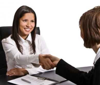 Image of woman shaking another woman's had in a professional setting